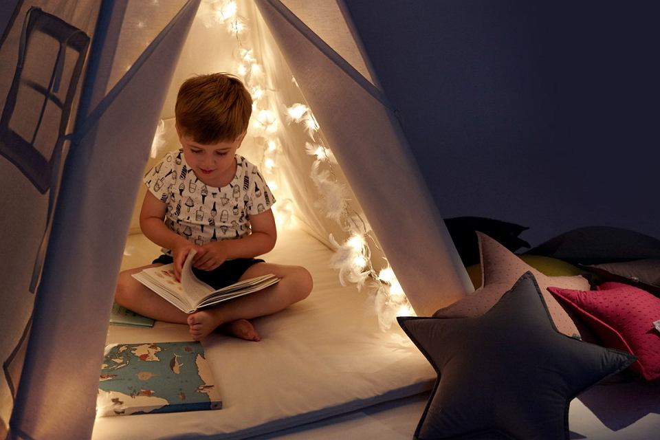 dziecko w namiocie bawiące się, czytające